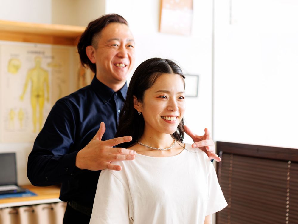 院長が患者さんの肩に手を当て、動きを確かめている様子