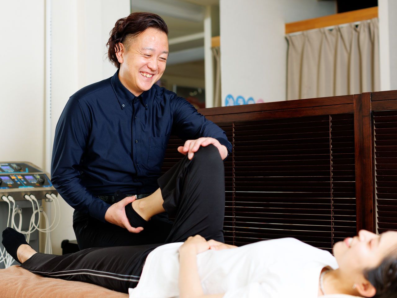施術ベッドに横になった患者さんの首まわりを、院長が手で確認している様子