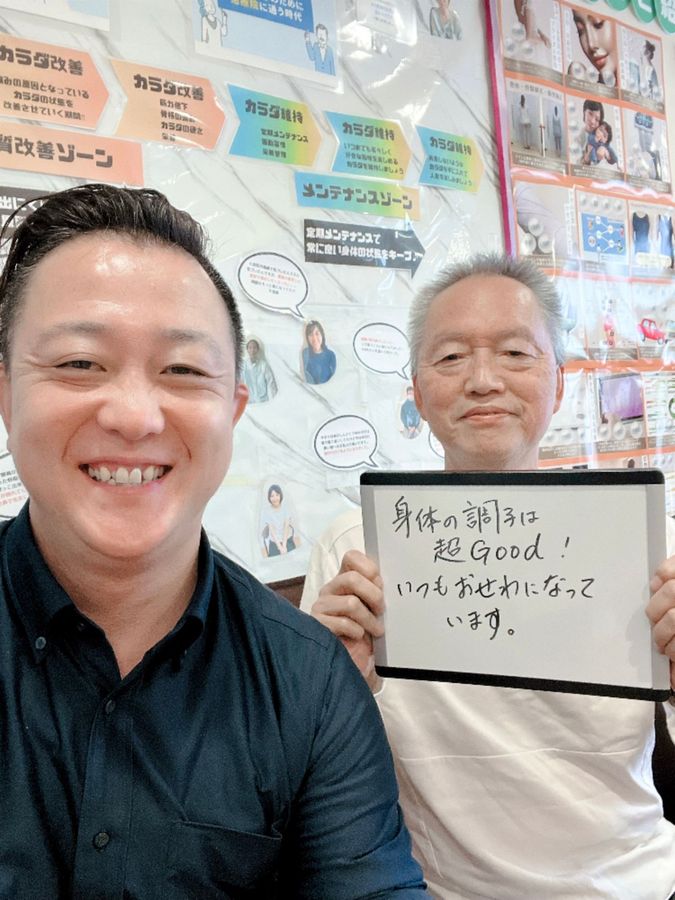 院長と男性の患者さん　ホワイトボードに「身体の調子は超Good！いつもおせわになっています」