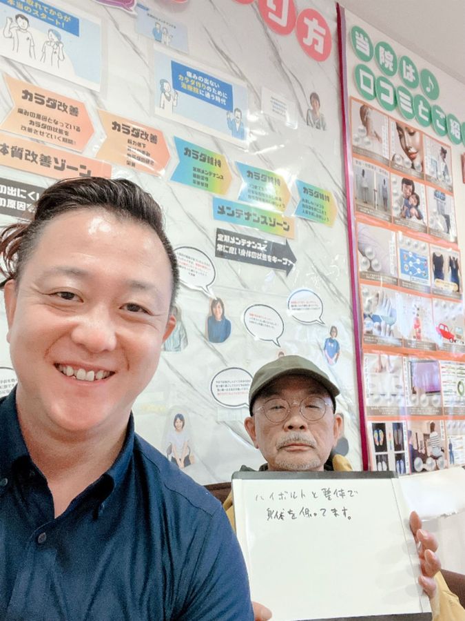 院長と男性の患者さん　ホワイトボードに「ハイボルトと整体で身体を保ってます」