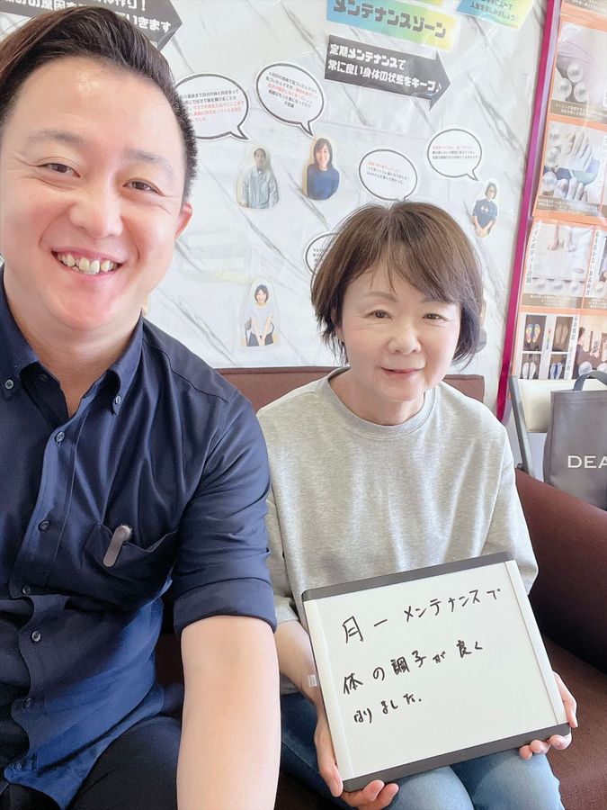 院長と女性の患者さん　ホワイトボードに「月一メンテナンスで体の調子が良くなりました」