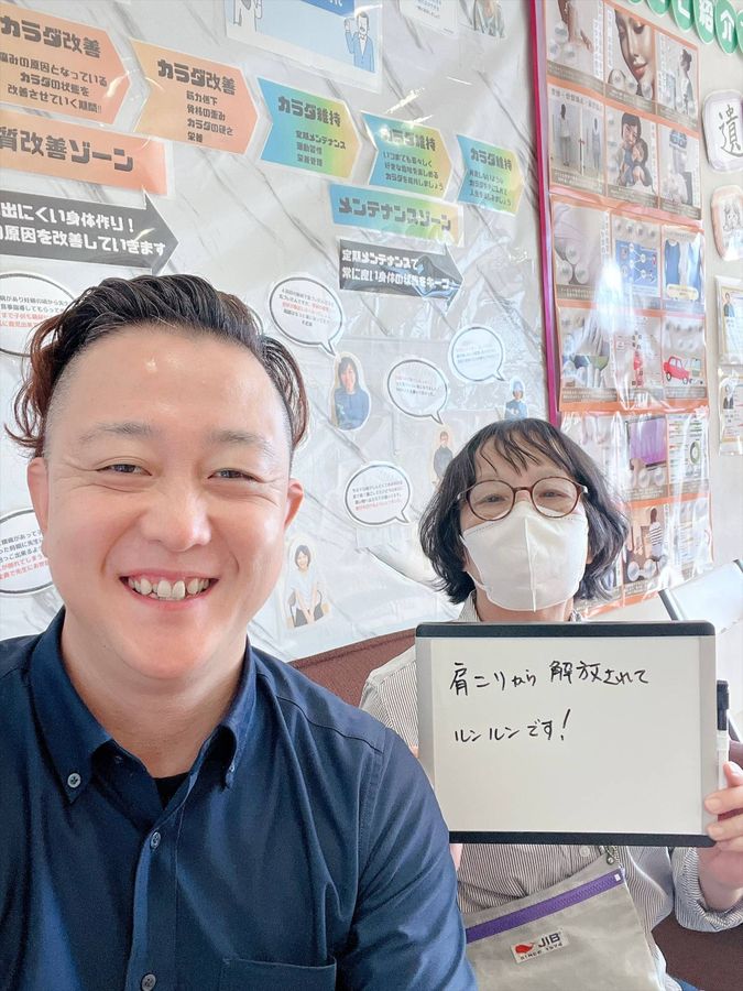 院長と女性の患者さん　ホワイトボードに「肩こりから解放されてルンルンです！」