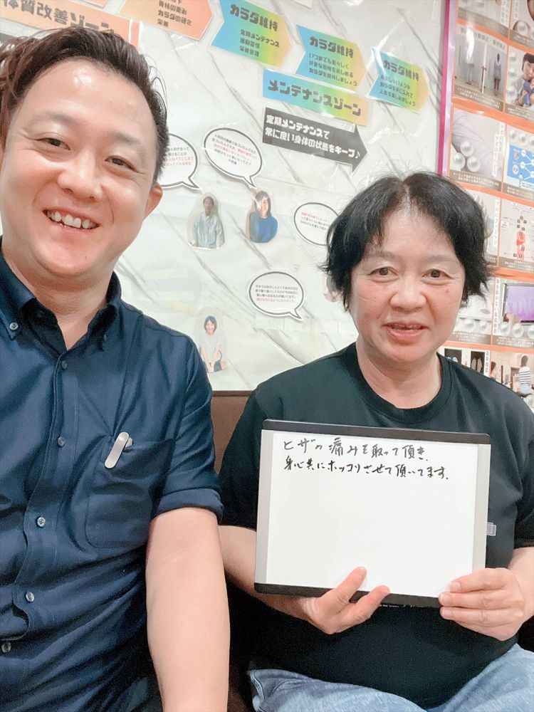 院長と女性の患者さん　ホワイトボードに「ヒザの痛みを取って頂き、身心共にホッコリさせて頂いてます」
