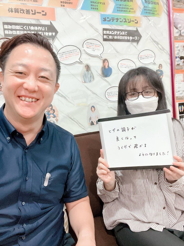 院長と女性の患者さん　ホワイトボードに「ヒザの調子が良くなってライヴで飛べるようになりました！」